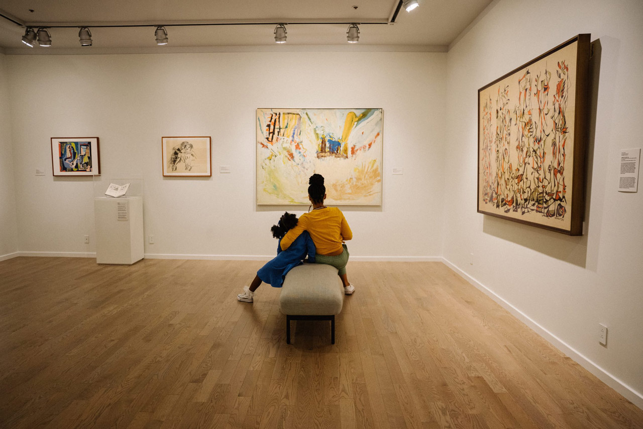 mother and daughter sitting on bench at newark museum of art looking at a painting